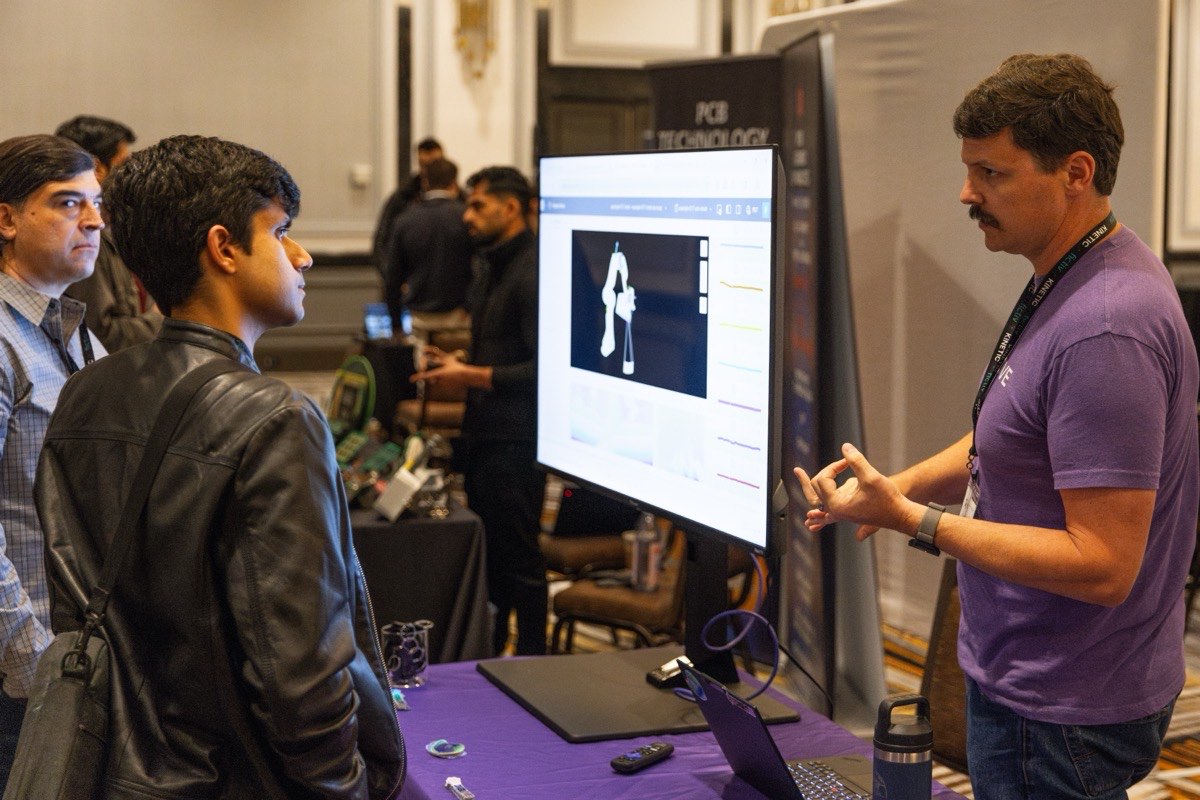 Hardware professionals discussing a demonstration on the Kinetic conference floor